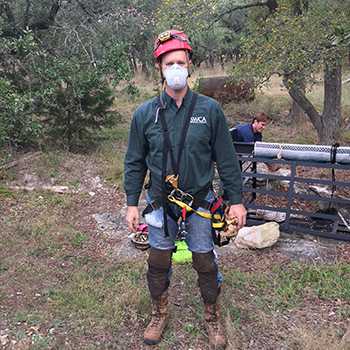Scientist posing with mask and other cave equipment 