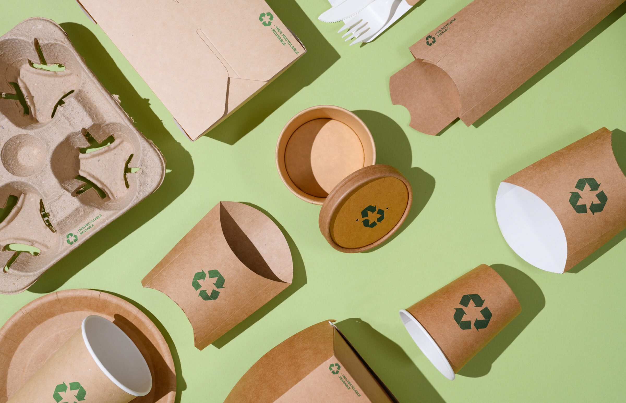 Disposable eco-friendly packaging with a recycling sign on a green background.