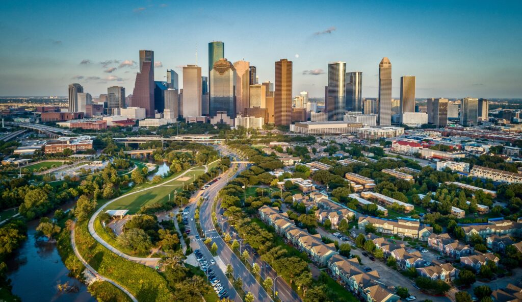 Houston, Texas Skyline At Sunset showing a stream or bayou, houses, and downtown Houston.