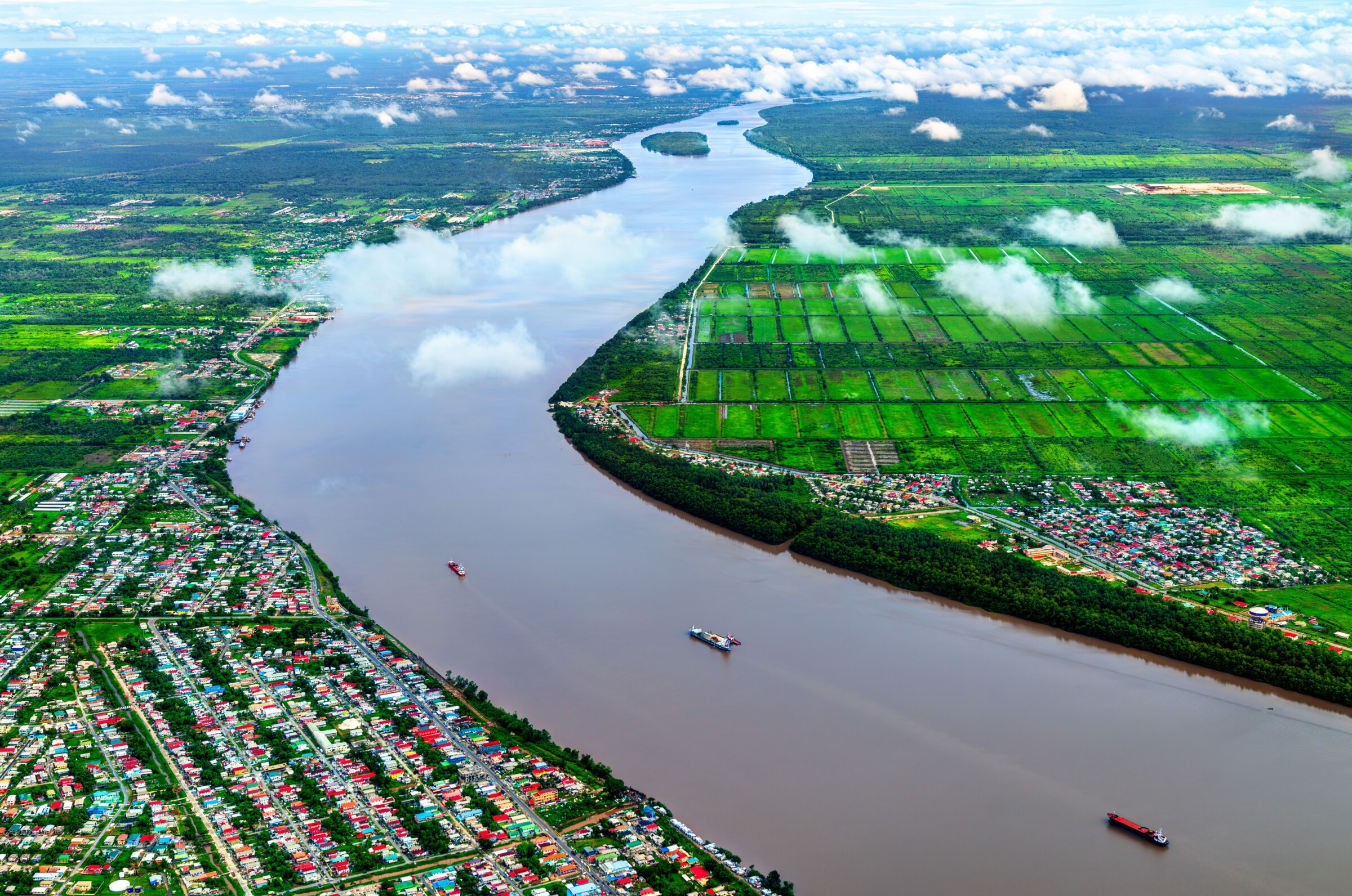 Aerial view of the Demerara river south of Georgetown in Guyana, South America. The image shows houses and fields alongside the river.