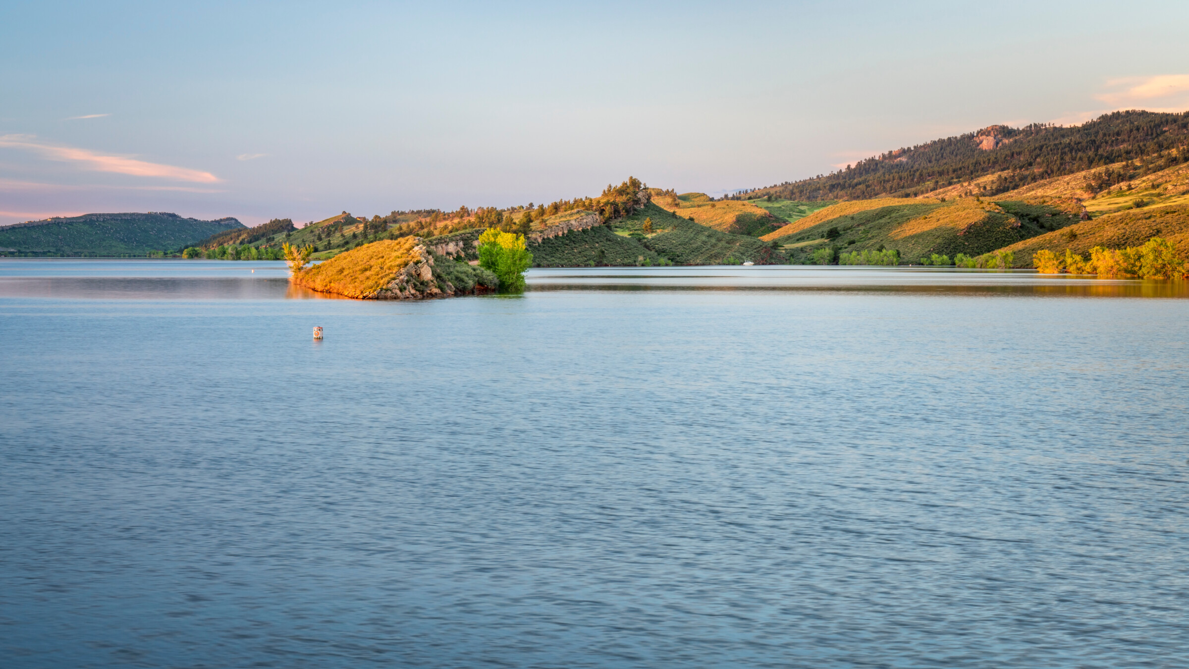 Horsetooth reservoir showing a large body of water with hills covered in green and yellow vegetation.