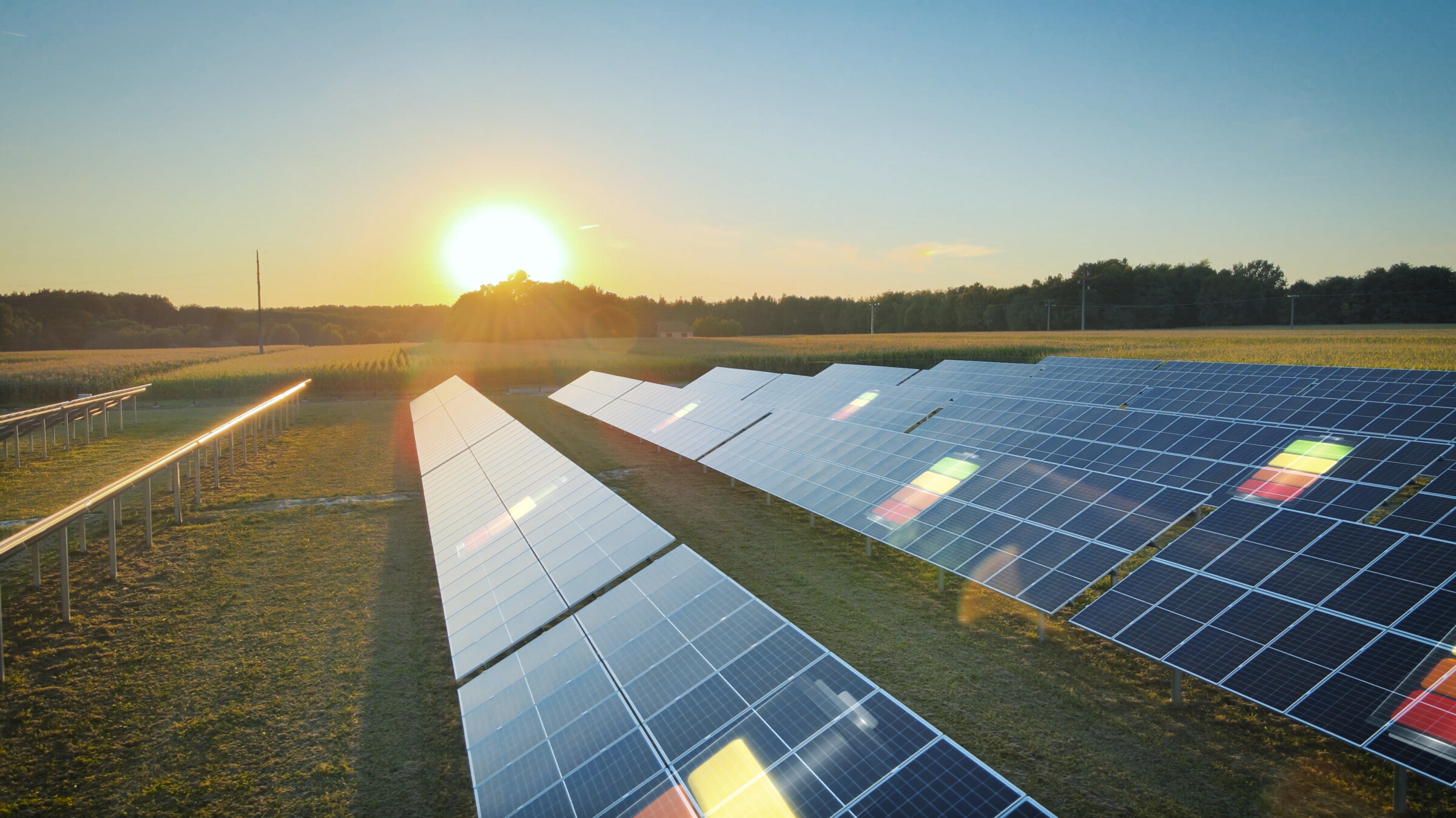 Large solar panel field at sunset with a 3D graphic of a battery representing energy storage and charging