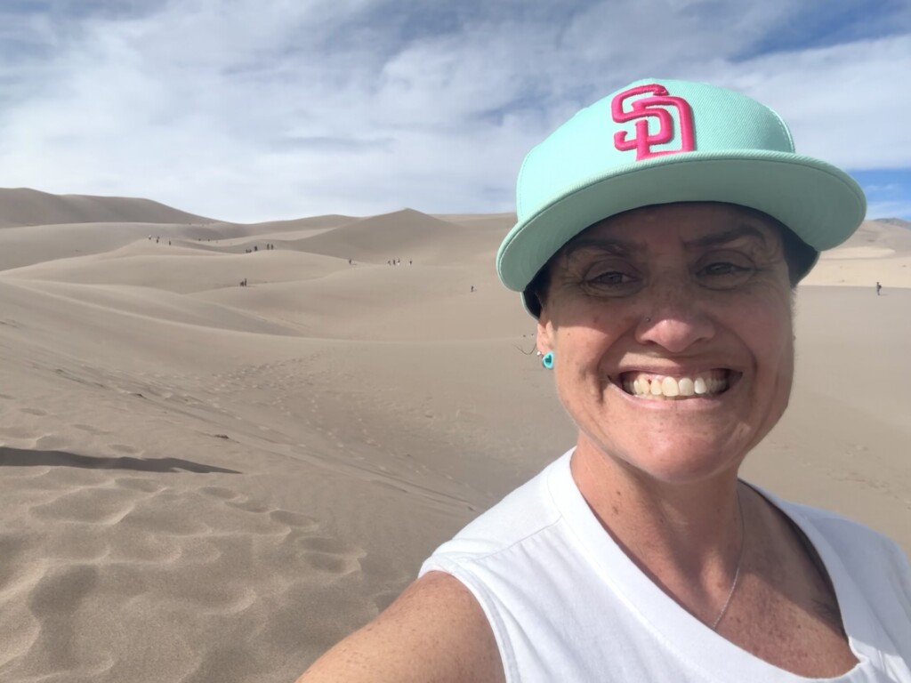 Lindsay Teunis smiling in front of the Great Sand Dunes landscape in Colorado.