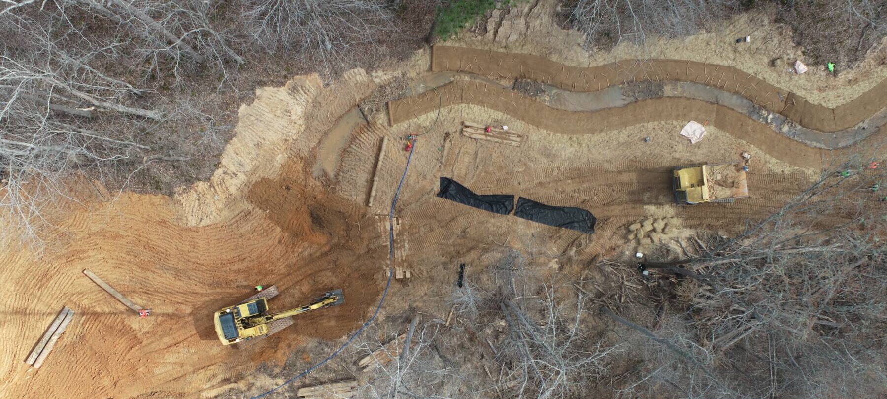 Overhead view of construction equipment in a forest working on stream restoration.