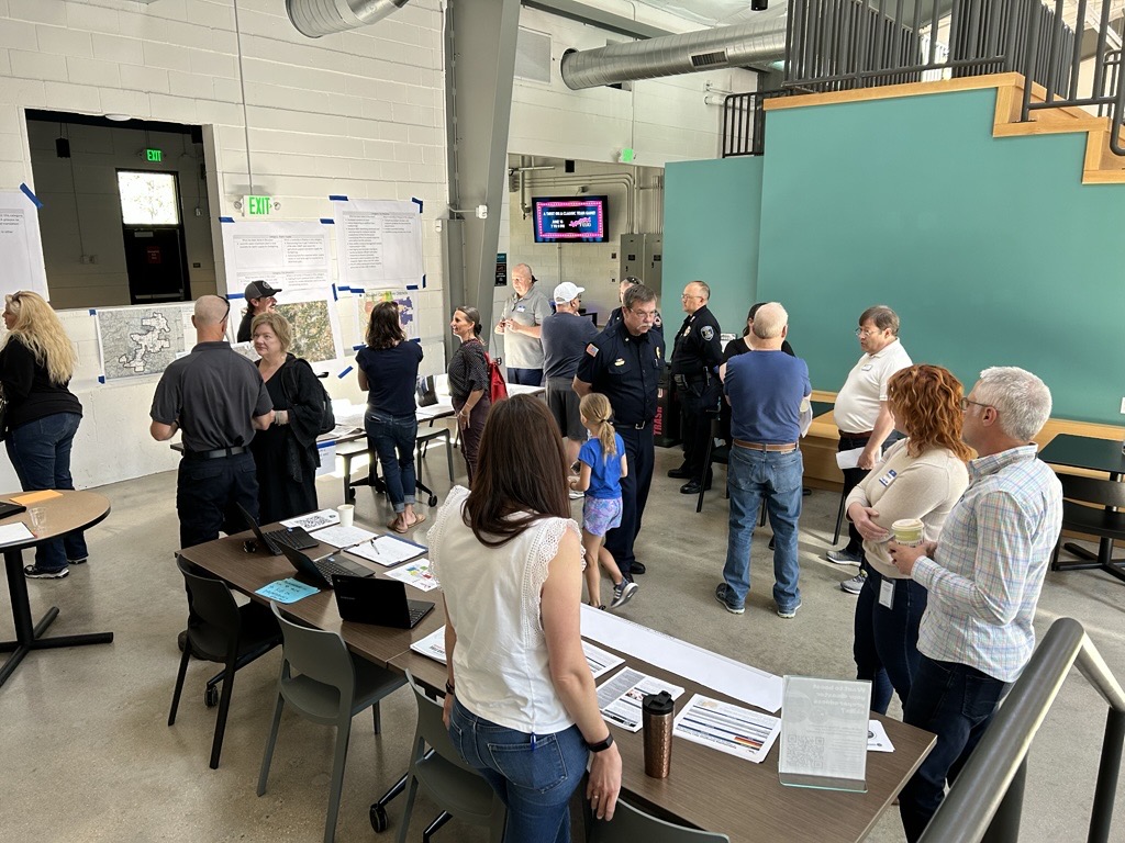 A group of people in a room with maps, figures and papers all around. 