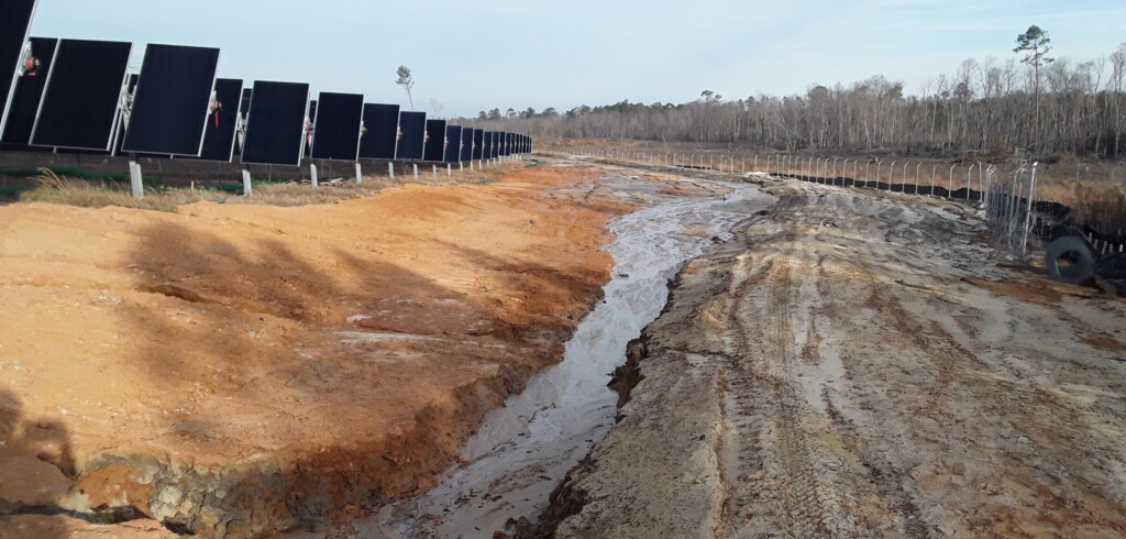 A gulley is shown next to solar panels that was created by channelized stormwater runoff. 