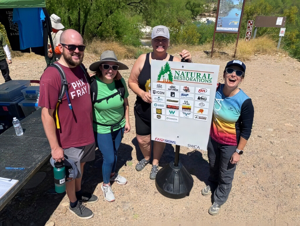 Michelle and three other people standing next to a Natural Restorations sign. 