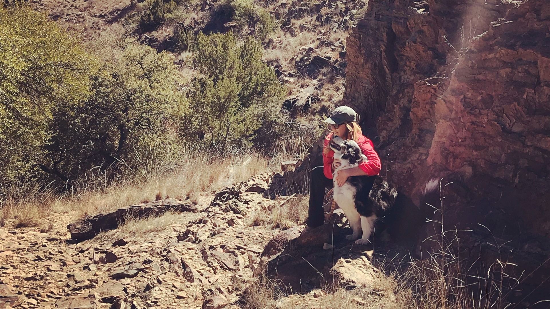 Sydney Lance with her dog kneeling next to a large rock.